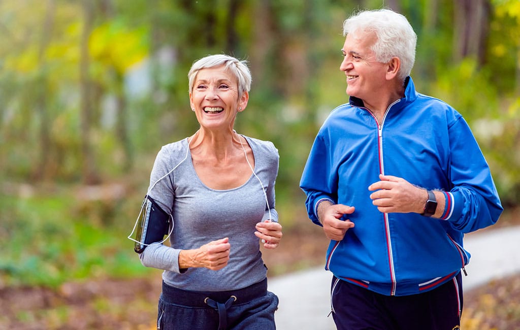 Older couple jogging outdoors with great smiles from dental restoration at Evergreen Dental in Palmer, Alaska.